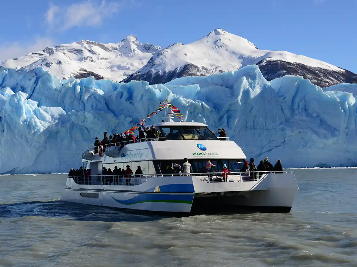 Grupo de turistas en cubierta de catamarán frente a grietas del Glaciar Perito Moreno, Brazo Rico, Parque Nacional Los Glaciares.