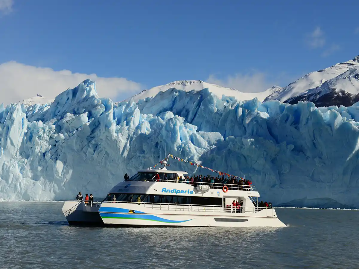 Navegación en catamarán frente a la pared sur del Glaciar Perito Moreno, Lago Argentino, tarde de sol con cielo despejado.