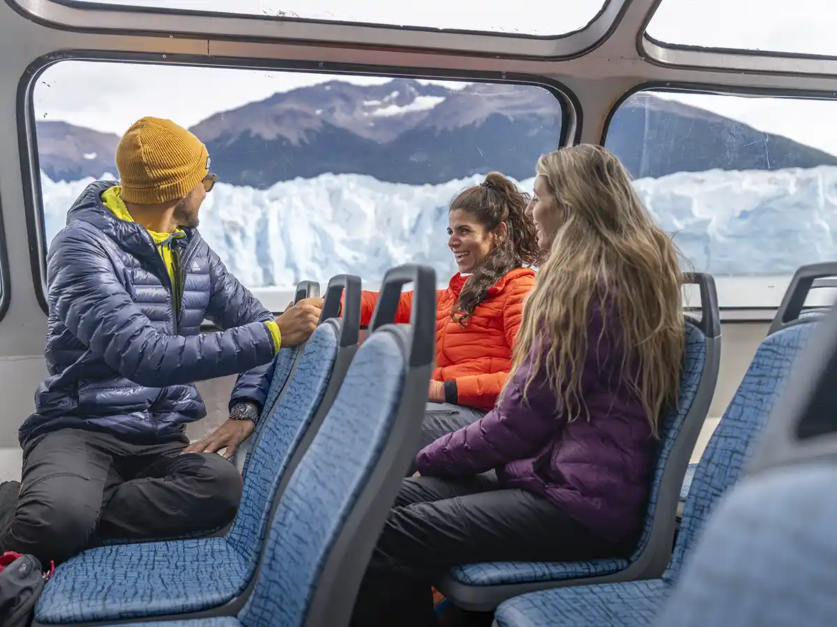 Turistas disfrutando vista panorámica del Glaciar Perito Moreno desde el interior de un catamarán, navegación por el Brazo Rico.