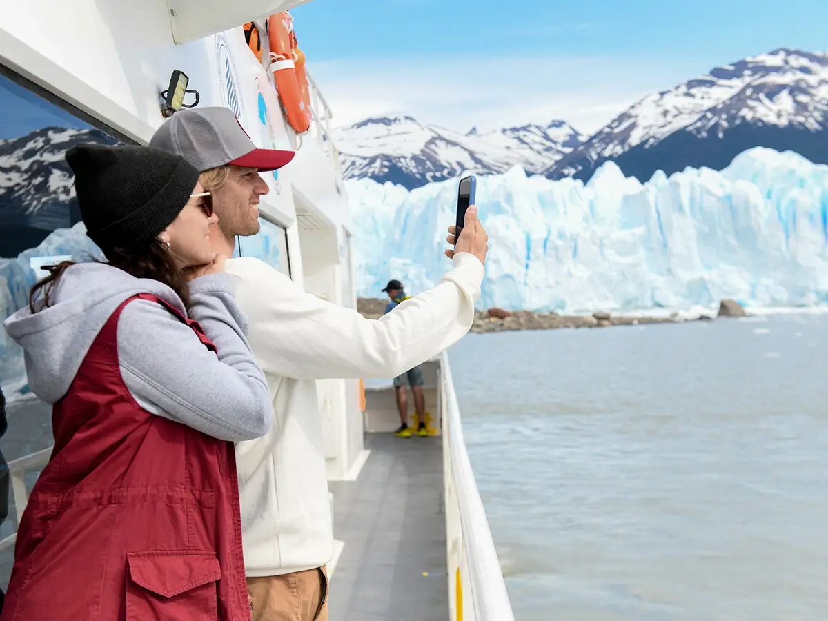 Turistas fotografiando la pared sur del Glaciar Perito Moreno desde la cubierta de una embarcación en el Brazo Rico.